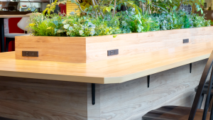 wooden bar with planter in center. Power charging stations mounted for customers