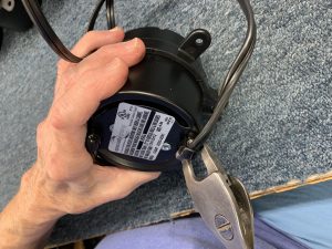 hand using pliers to remove strain relief bushing from downlight